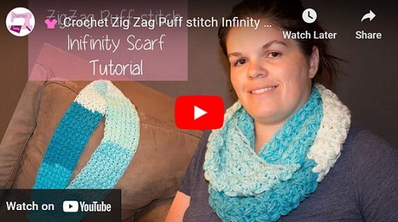 A woman is wearing an infinity scarf crocheted in a zig zag puff stitch