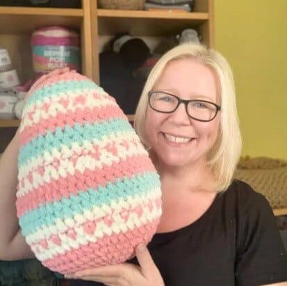 woman holding a big crocheted Easter egg