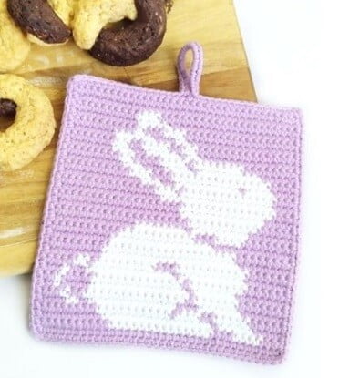 A white bunny on a lilac background on a crocheted pot holder