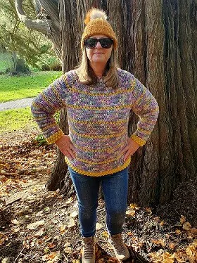 woman in the woods wearing a crochet jumper and jeans