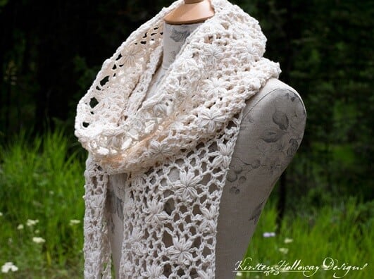 A crochet lace scarf is styled on a mannequin