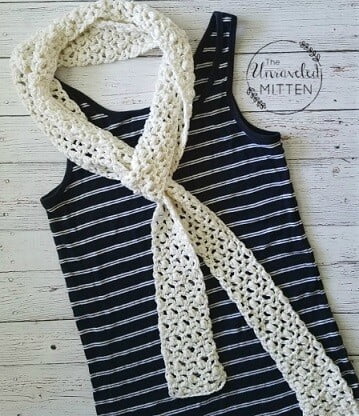 flatlay of a black and white striped vest top and white crochet lace scarf