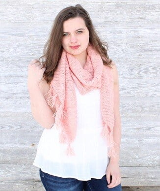 a young woman is wearing a white sleeveless top, jeans and a pink scarf