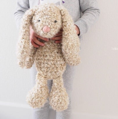 A child is holding a floppy plush bunnie