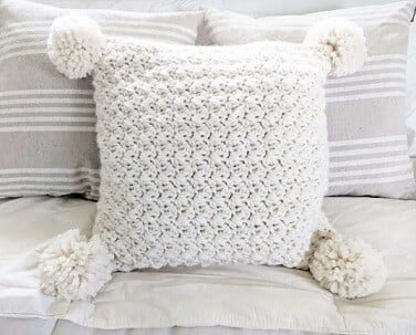 pillow with pom poms in white on a white sofa