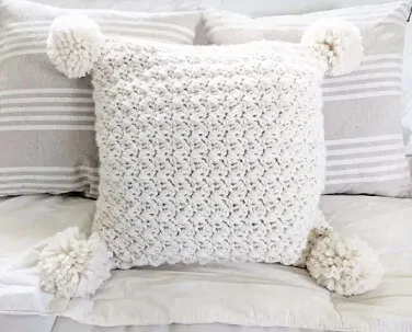 pillow with pom poms in white on a white sofa