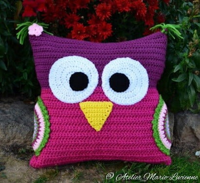 A cushion crocheted in the shape of an owl in pink and purple