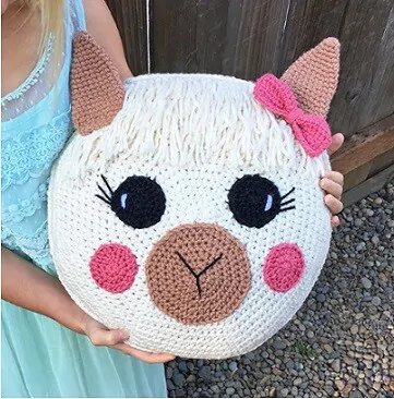 a young girl is holding a llama pillow