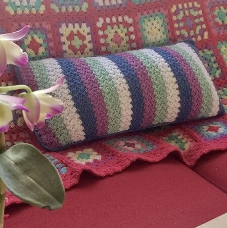 striped rectangular cushion on a sofa with a granny square blanket
