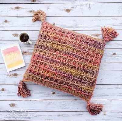 Multicoloured throw pillow crocheted in waffle stitch with tassels on the four corners