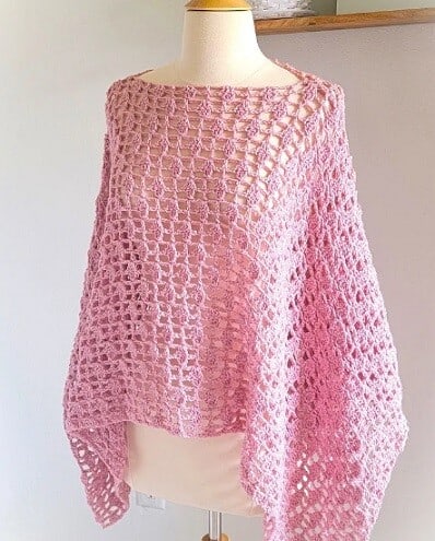A lacy pink poncho is styled on a mannequin