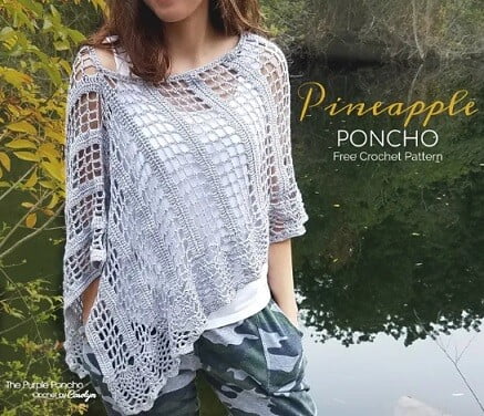 A woman is standing near a lake wearing a lacy crochet poncho