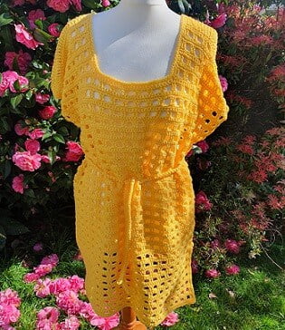 the front view of a beach cover up crocheted in sunflower yellow styled on a mannequin