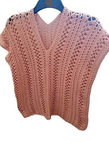 A pink lacy top is hung on a coat hanger