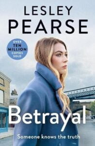 book cover for Betrayal by Lesley Pearse. A woman is standing in the middle of a road and in the background, a train is passing by