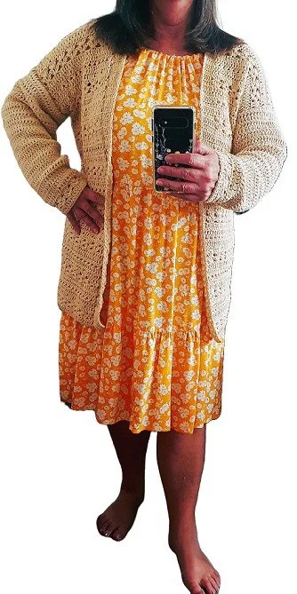 a woman is wearing an orange dress and a oat coloured cardigan