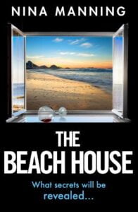 book cover for The Beach House by Nina Manning. Looking out of a window to a beach scene. A carafe almost empty is on its side on the window cill