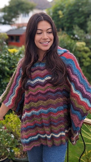 A woman wearing a crochet poncho and jeans