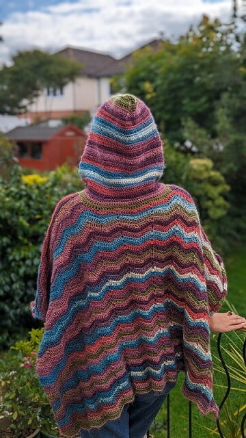 A woman is facing away wearing the hood up on a poncho