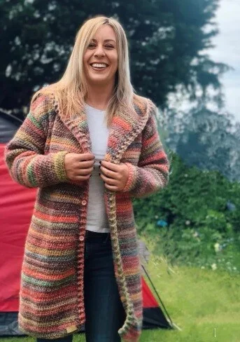 A woman is standing in front of a tent wearing a duster chunky cardigan