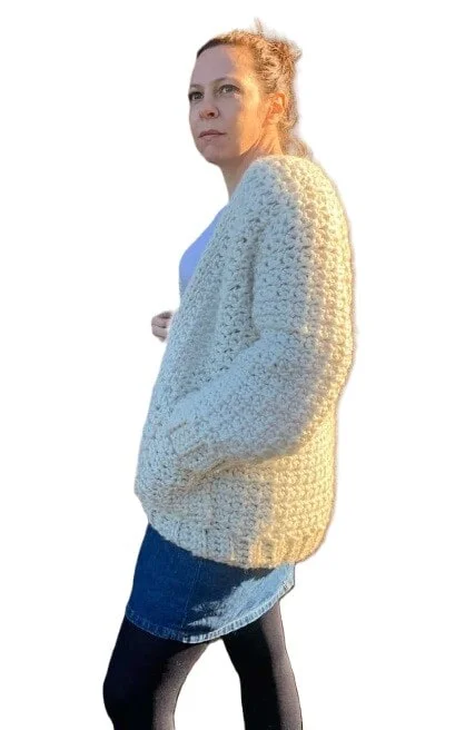 A woman is wearing a chunky cardigan and jeans