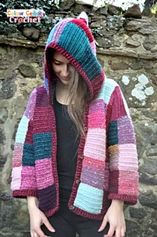 A woman is wearing a brightly coloured cardigan with the hood up