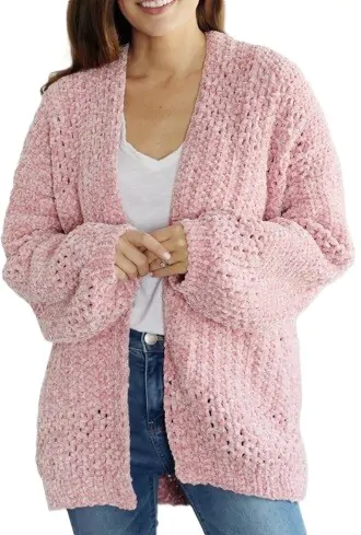 An oversized pink chunky cardigan is styled on a woman wearing a white tshirt and jeans