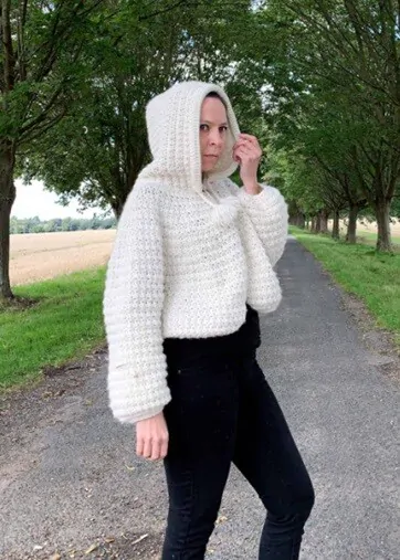 A woman is wearing a cape crocheted in chunky yarn