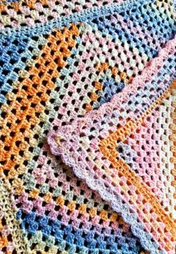 A granny square blanket with the corner folded over showing the shell border