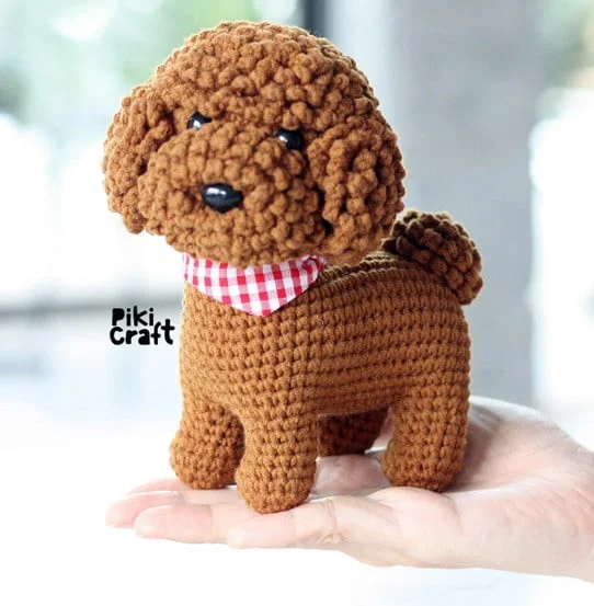 A brown crocheted Poodle is resting on a hand