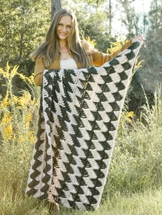 A woman is standing up holding a blanket with a zig zag pattern