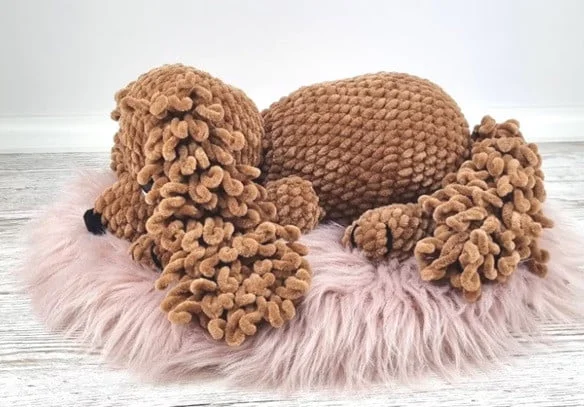 A crocheted Cocker Spaniel is laying on a fur rug