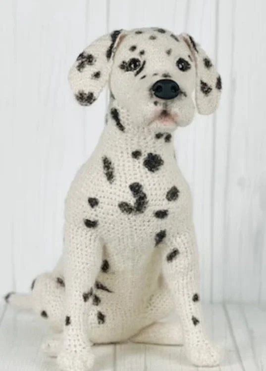 A Dalmation crochet dog is sitting up on the floor