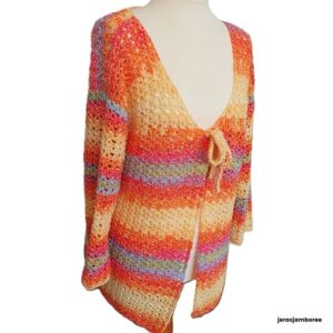 A crochet cardigan in orange, yellow, purple, green and blue is styled on a mannequin