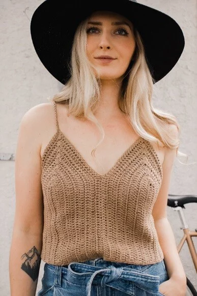 A woman is wearing a beige tank top and jeans