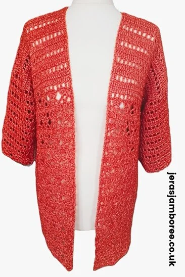 A summer cardigan in orange is styled on a mannequin showing the front