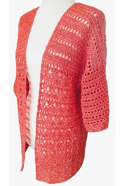 Coral-colored crochet summer cardigan displayed on a mannequin, featuring a mix of open lace stitches and solid rows with elbow-length sleeves and a lightweight drape.