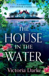 book cover for The House in the Water by Victoria Darke. There is a house in the background on an island with lily pads close to the bank
