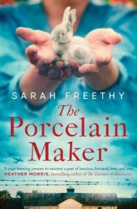 Book cover for The Porcelain Maker by Sarah Freethy. Hands are holding out a lifelike rabbit with the background blurred