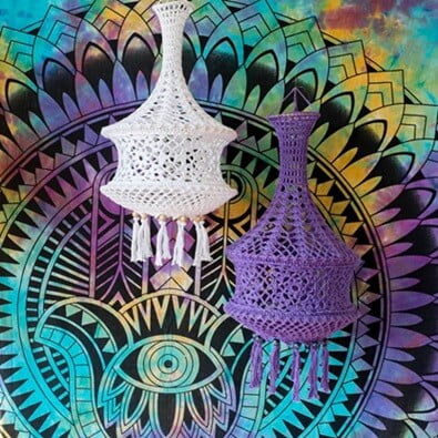 2 crocheted nammu lampions are hung up with a bright and colourful background