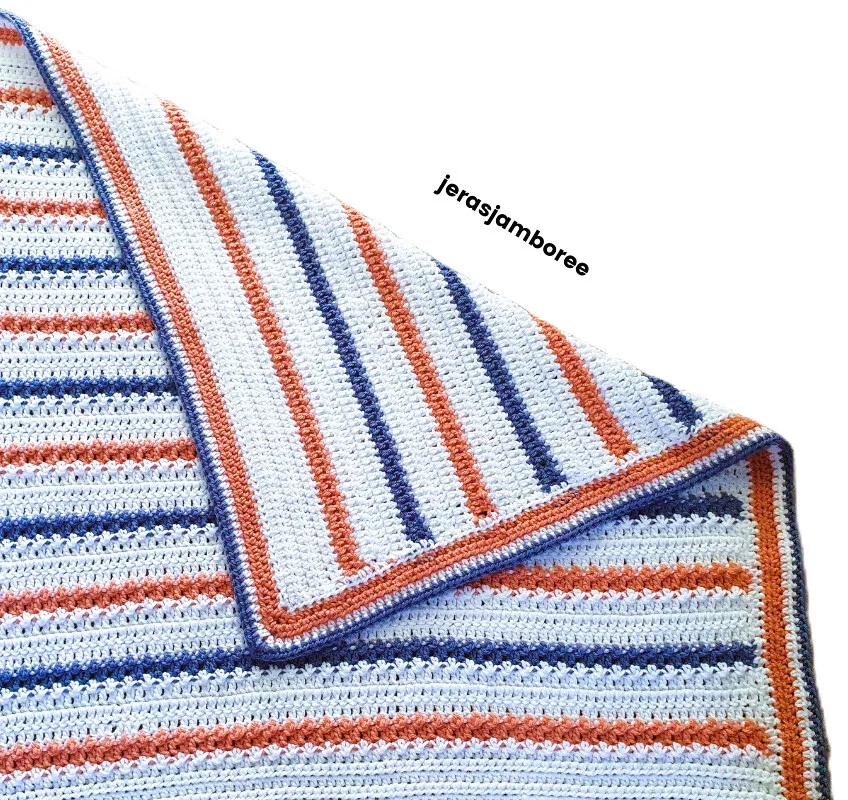 A striped blanket is laid flat with the top right corner folded over