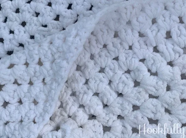 A blanket crocheted in chunky yarn in white in a continuous granny square