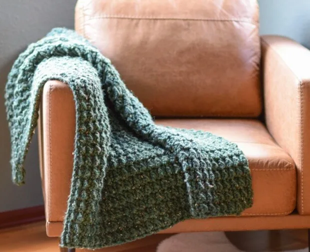 A green throw is draped over the arm of a sofa