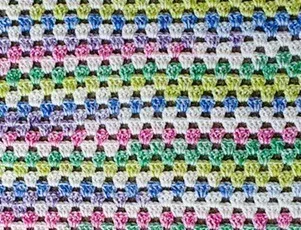 A close up of the granny stitch worked in self-striping yarn