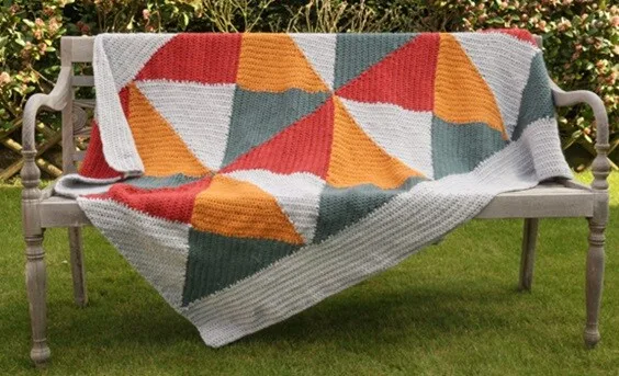 A bright and colourful blanket is draped over a garden bench