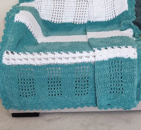Blanket in green and white is draped over a sofa