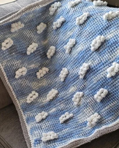 A blue blanket with white fluffy clouds is laid flat