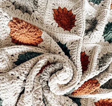 A blanket crocheted in granny squares is bunched up into a swirl