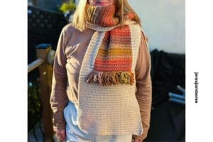 A woman is wearing a scarf looped around her neck