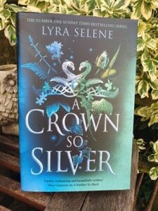 book cover for A Crown So Silver by Lyra Selene. Two mythical creatures intertwine above a crown